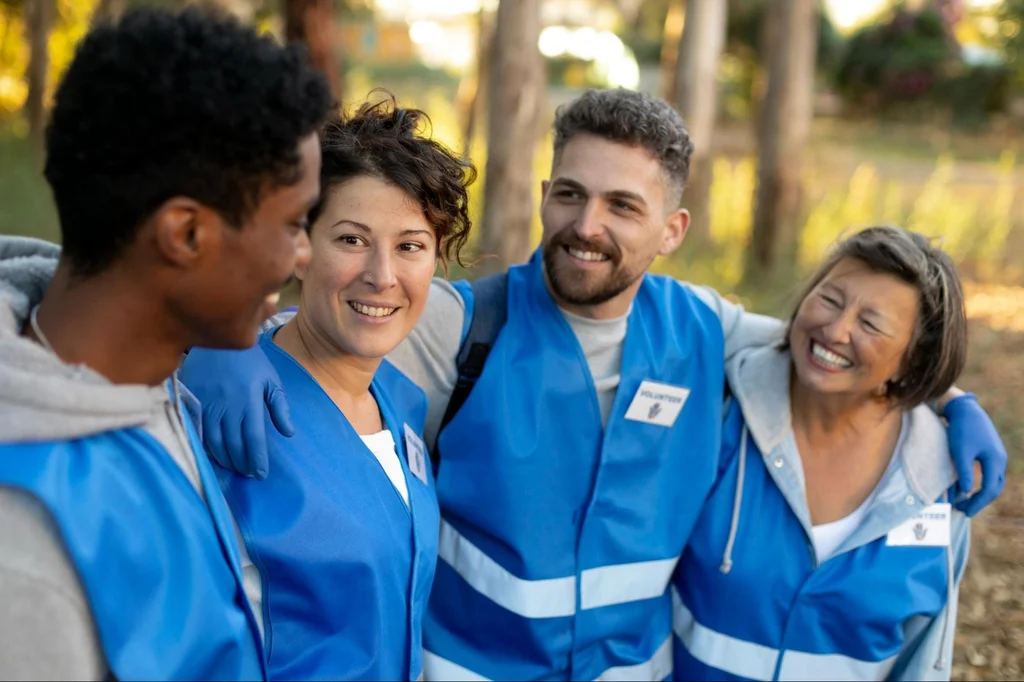 Group of happy volunteers wearing blue safety vests at outdoor nonprofit service event showing community engagement